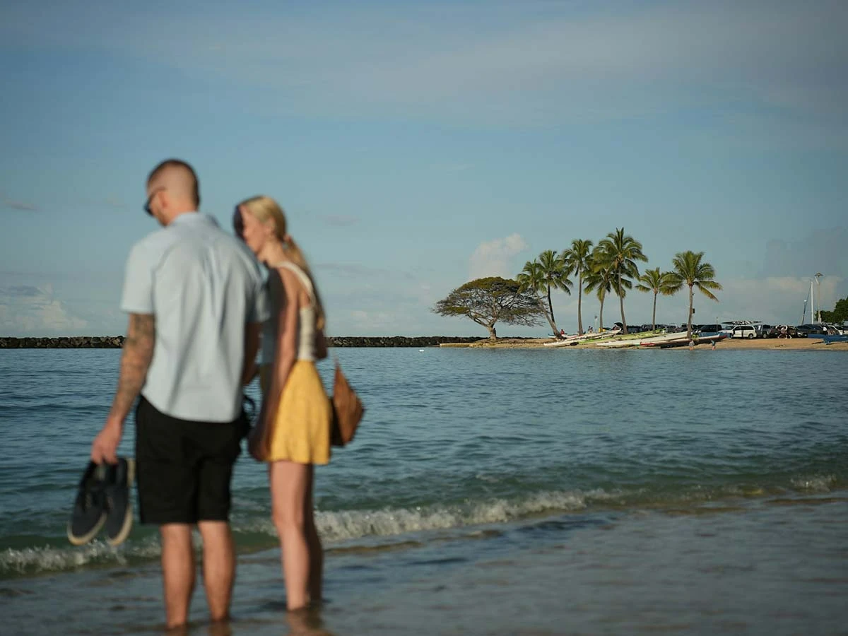 A young couple standing on a tropical beach looking at the ocean, symbolizing the dream of early retirement and FIRE lifestyle.
