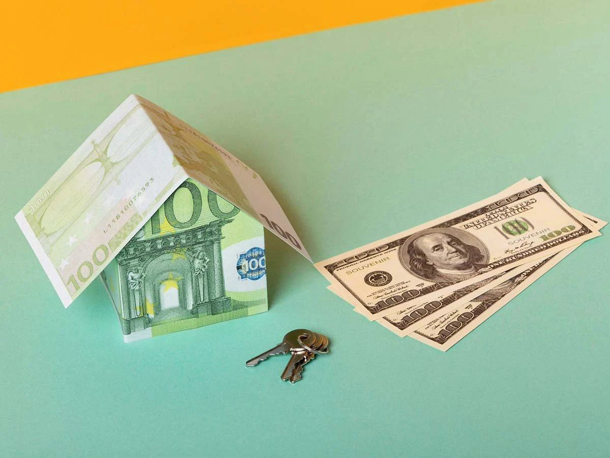 A house model made of currency with keys and dollar bills, representing investment for residency and passive income abroad.