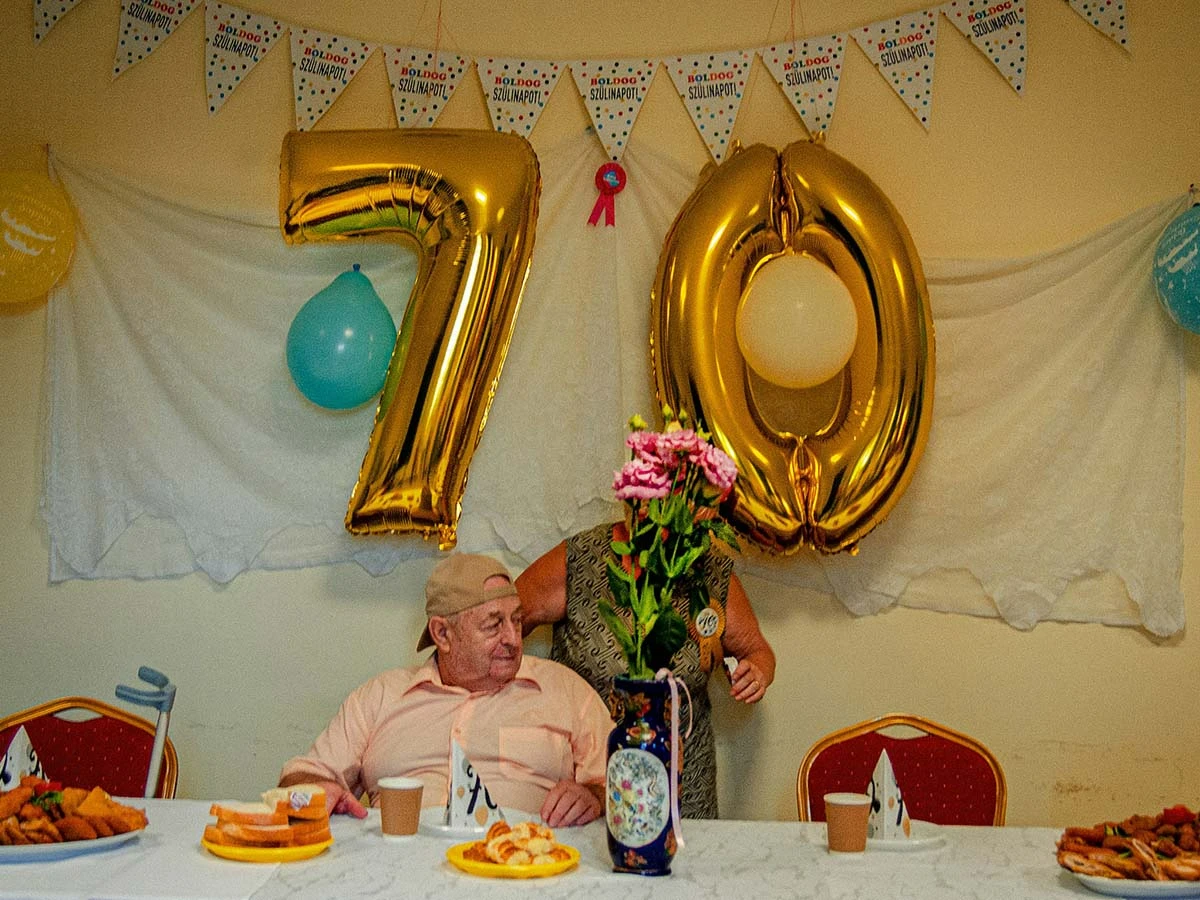 A 70th birthday celebration with gold balloons and cake, representing a significant age milestone for retirement planning.