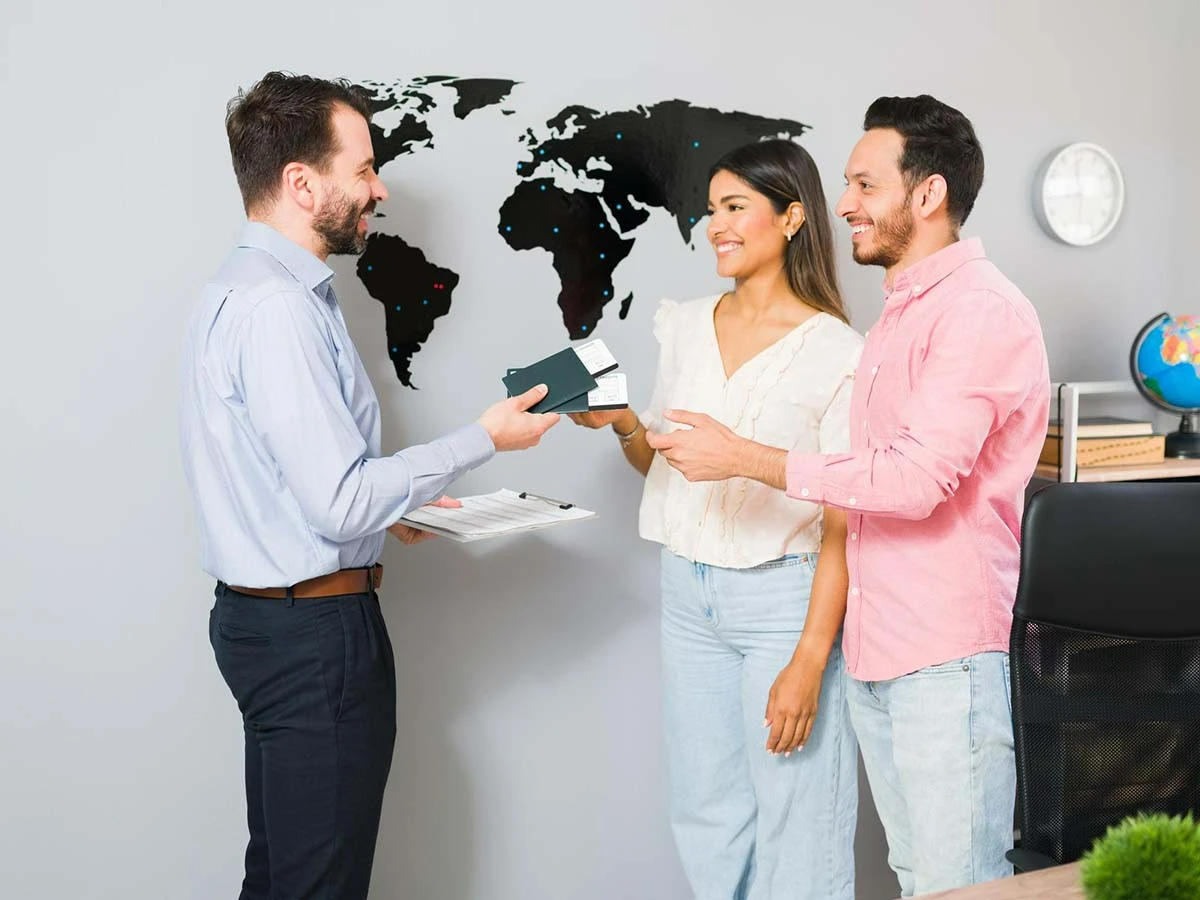 A professional consultant handing a passport to a couple at a desk with a world map background, representing the Brazil retirement visa application process.