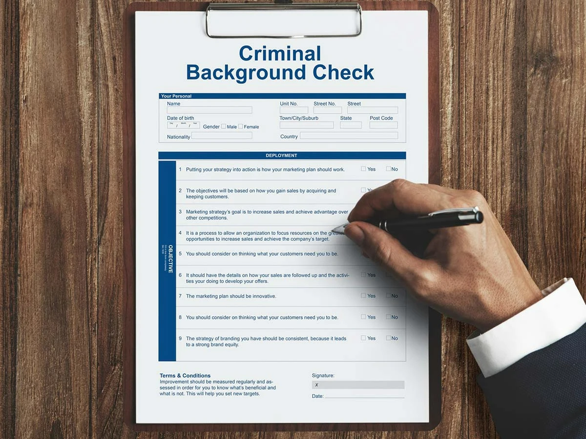 A close-up of a hand filling out an FBI criminal background check form for international residency applications.