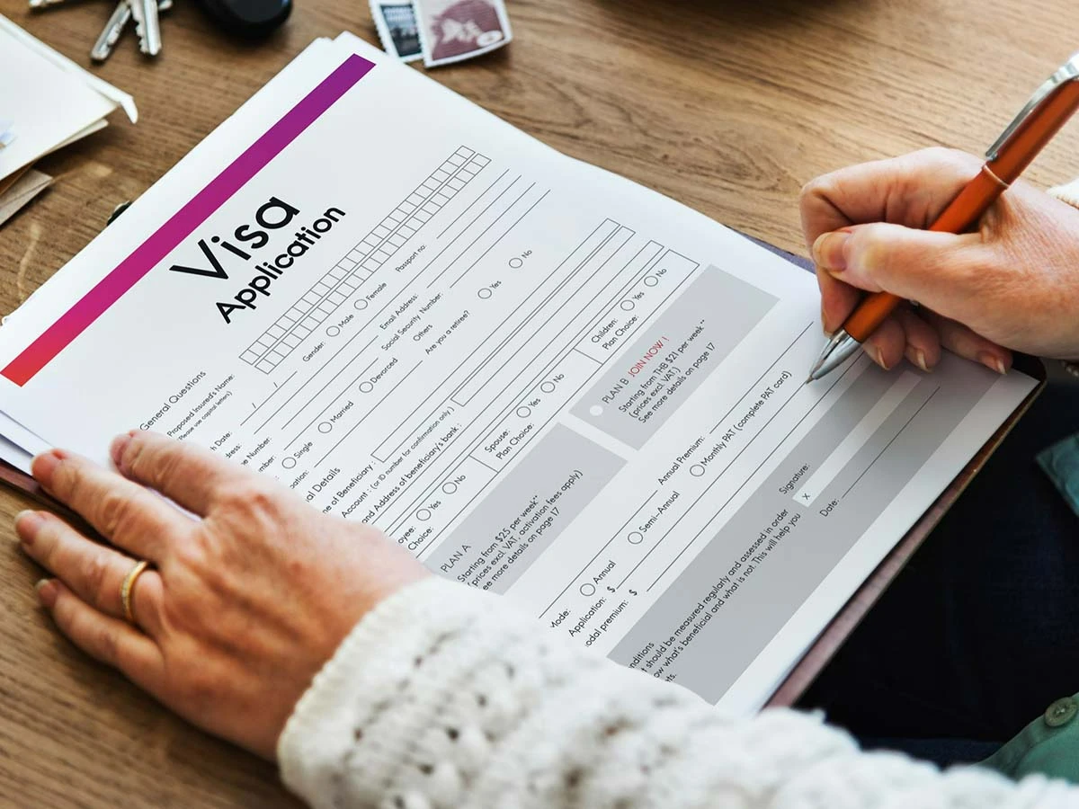 Close-up of hands filling out a formal Brazil visa application form on a wooden desk, part of the 2026 checklist for American retirees.