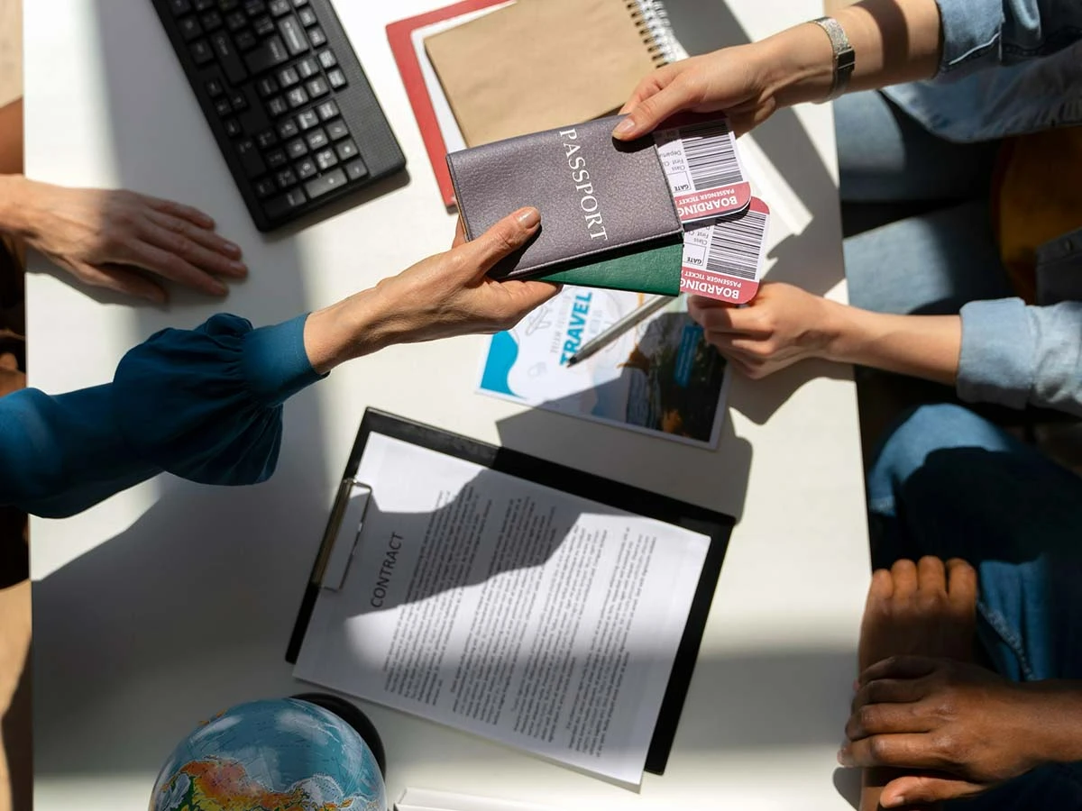 Hands exchanging passports and legal documents over a desk at an immigration office or law firm.