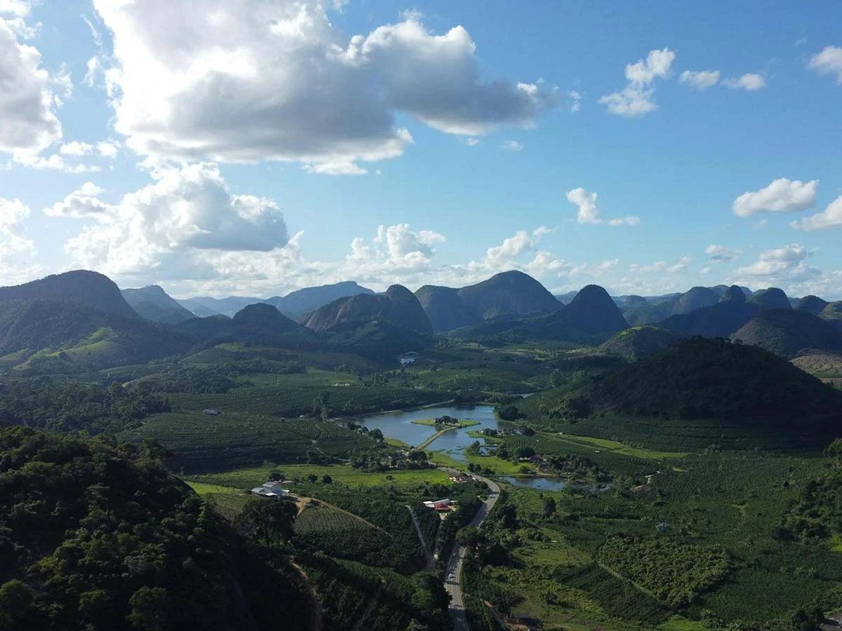 Panoramic view of the lush green mountains and valleys of the Brazilian highlands under a blue sky.