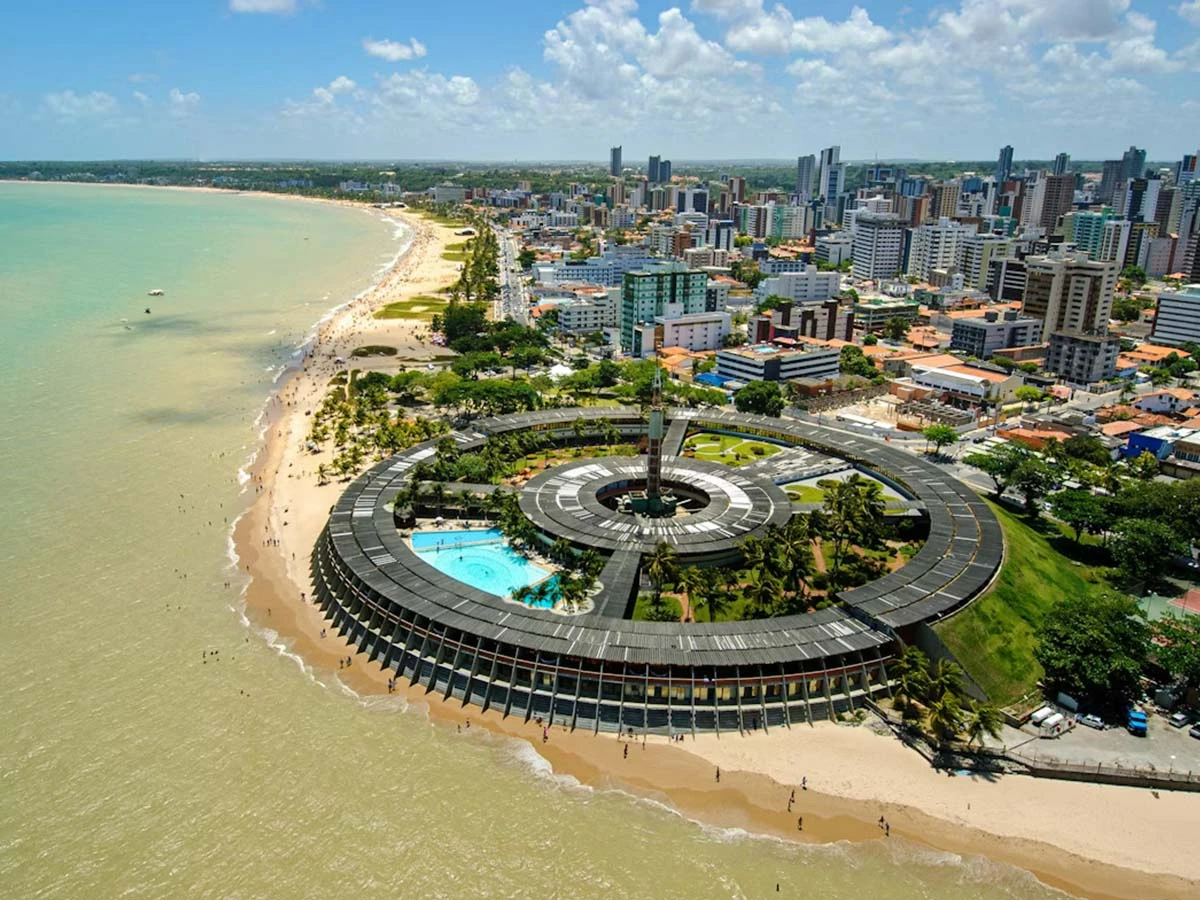 Aerial view of the João Pessoa coastline featuring the unique circular hotel architecture and turquoise ocean.