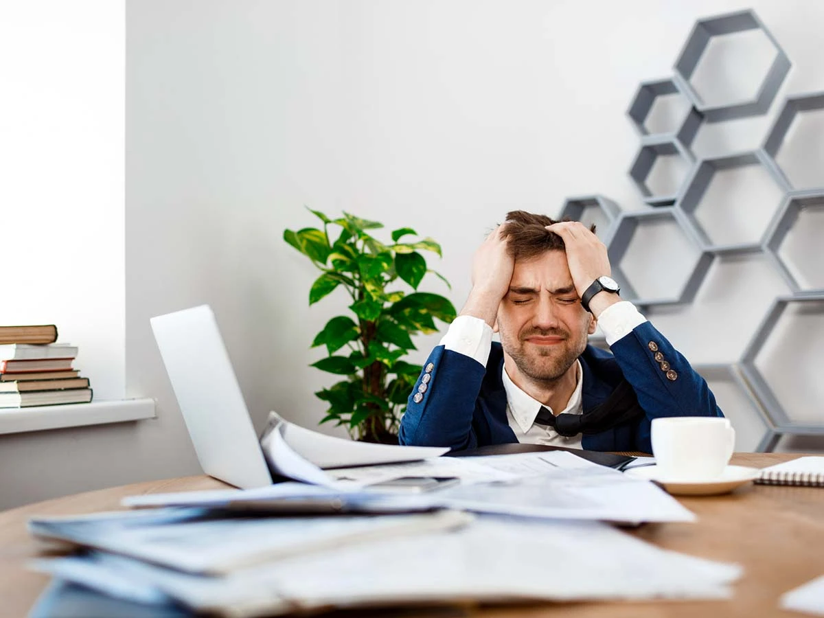A man looking frustrated at a desk piled with paperwork, representing the challenges of navigating Brazilian immigration bureaucracy.
