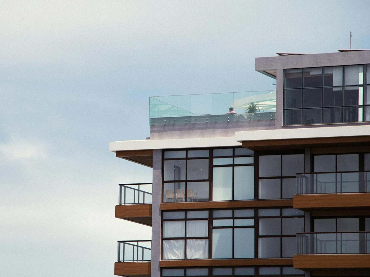 The exterior of a sleek, modern apartment building under a blue sky, representing secure gated community living for expats.