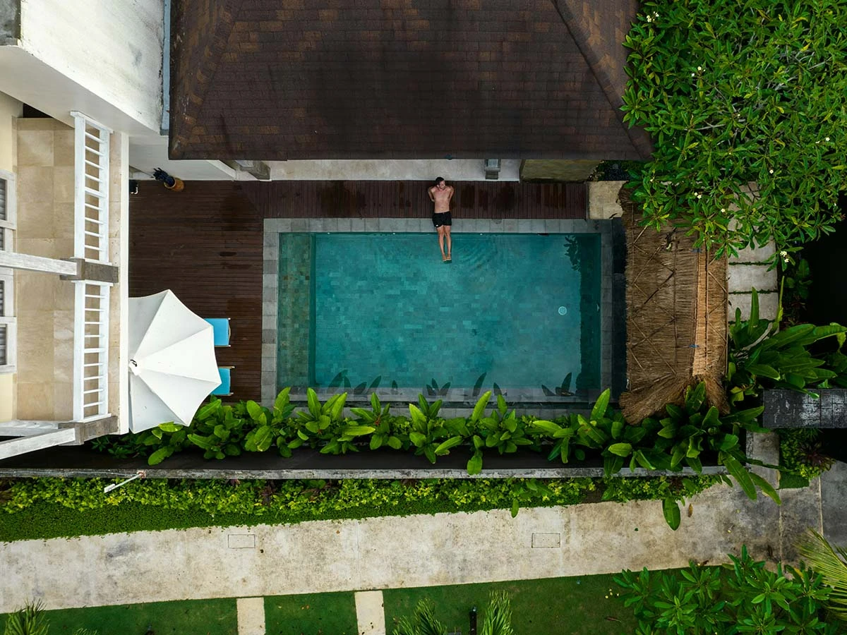 Aerial view of a private swimming pool and lush tropical gardens at a luxury expat villa in Brazil.