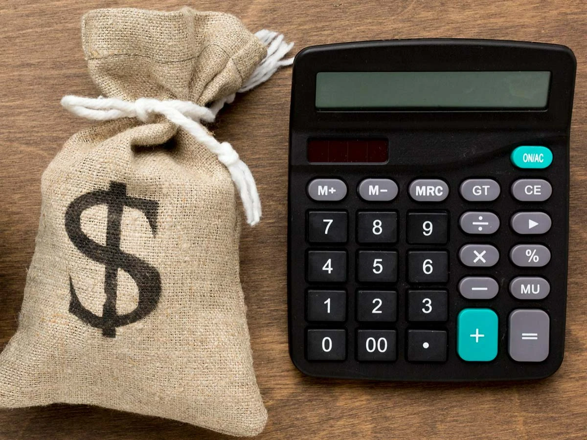 A burlap bag with a dollar sign, and a digital calculator on a wooden surface, symbolizing global tax planning and compliance for expats.