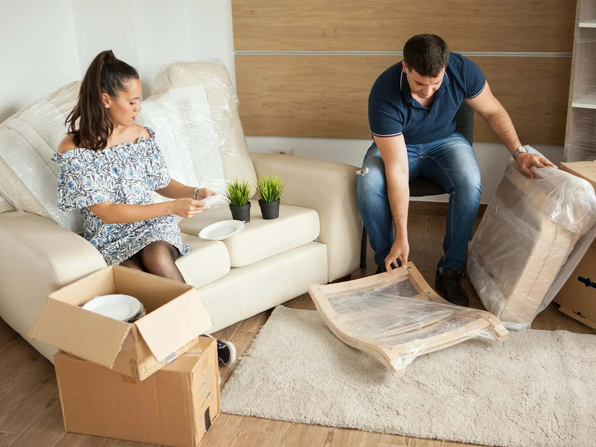 A young couple unpacking moving boxes in their new Brazilian apartment, representing the first steps of relocating abroad.