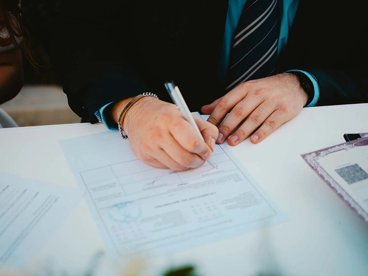 A close-up of hands signing legal documents for a double taxation agreement, providing tax certainty for UK expats in Brazil.