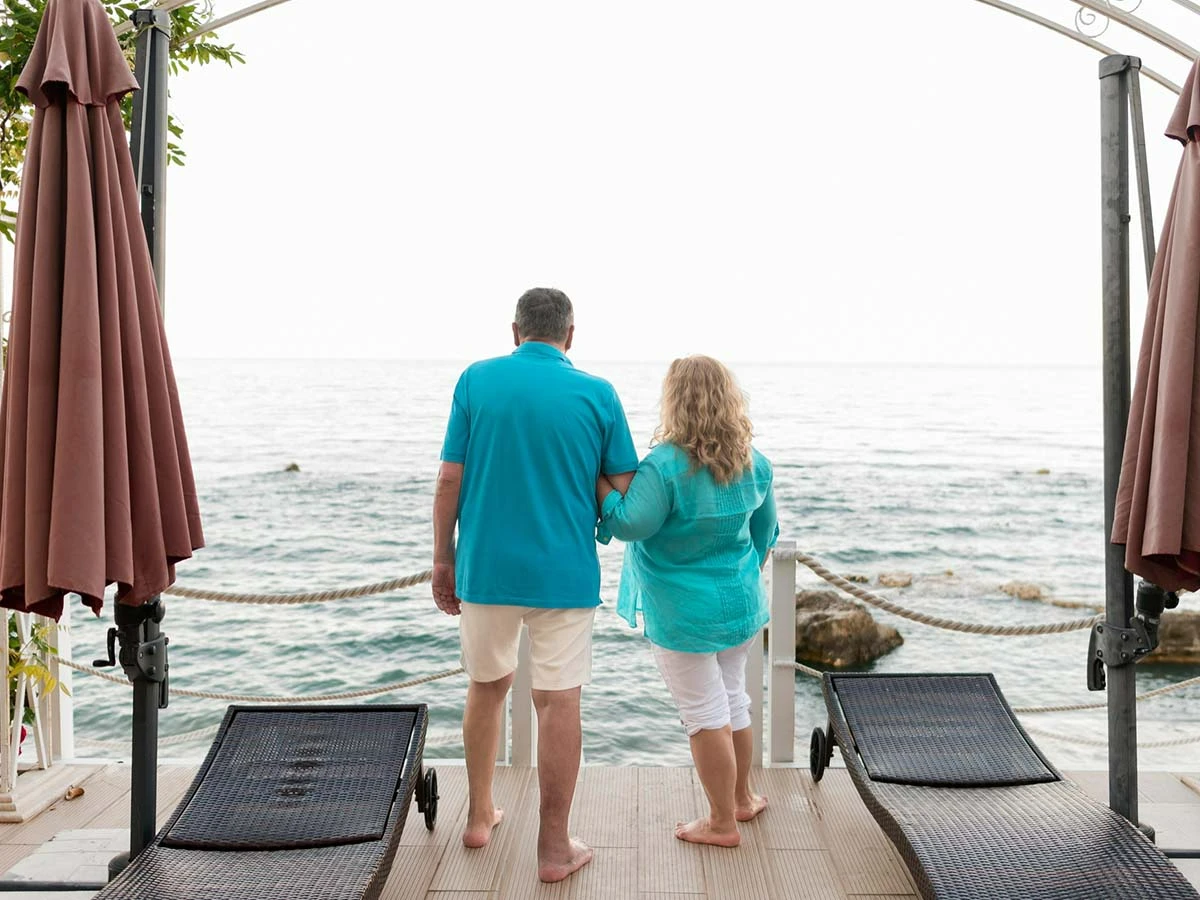A senior couple looking out at the ocean from a private balcony in Brazil, enjoying the fruits of their retirement planning.